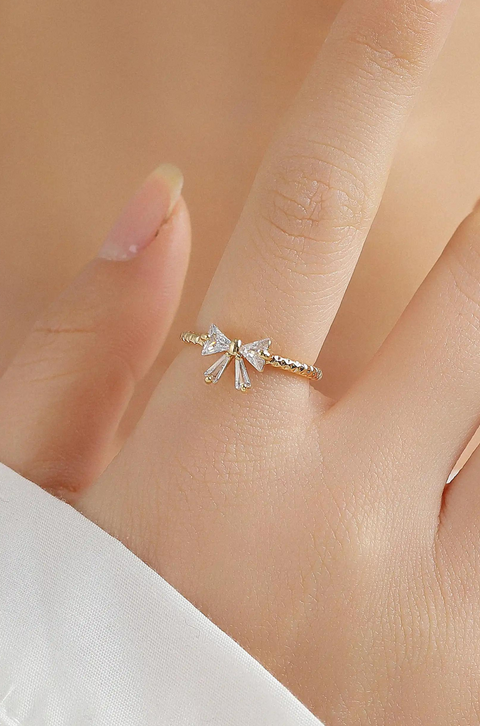 Bowtie sparkle ring accented with small sparkling gems on a slender gold band.