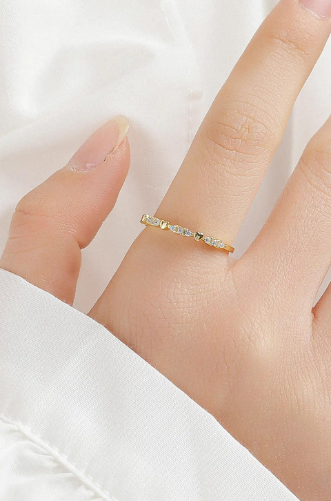 Our forever love ring featuring row of small, round, and clear sparkling stones with hearts in between, set into the band.