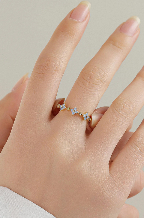 Flower ring with a scalloped design, featuring small blue flowers made of gemstones, creating a delicate, petal-like pattern around the band.