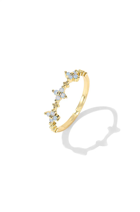 Flower ring with a scalloped design, featuring small blue flowers made of gemstones, creating a delicate, petal-like pattern around the band.