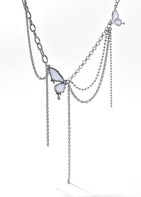 A butterfly necklace with a silver chain, adorned with two butterfly pendants and layered chains that drape with white gemstone accents.
