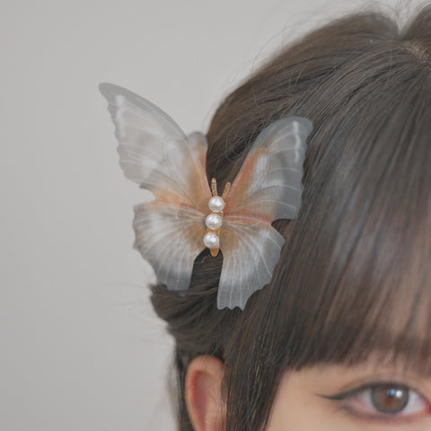 Butterfly hair clip with translucent wings and white pearls centerpiece.