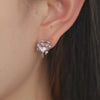 Heart stud earrings with a central pink gemstones surrounded by small, clear crystals.