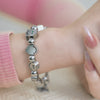A happy face bracelet in cute face charms, each with green colored gemstones eyes.