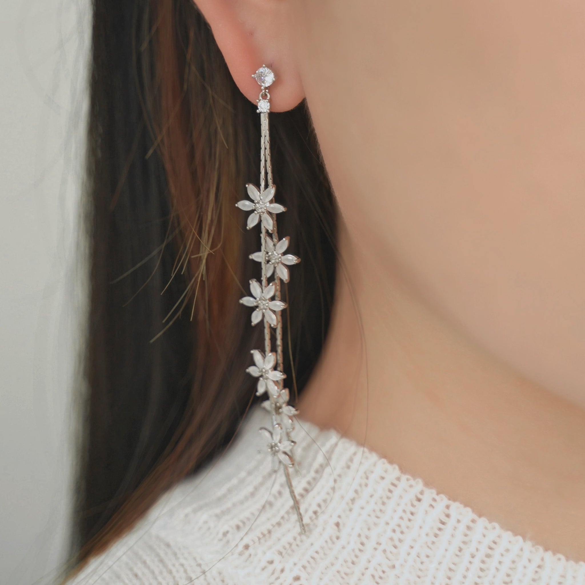 A long drop earrings with multiple small, sparkling floral earrings design trailing down.