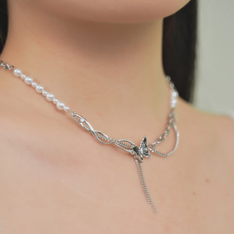 A lariat necklace that combines a string of pearls with a silver chain and a butterfly pendant.