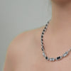 A gem leather necklace with a chain, interspersed with clear and black gemstones.