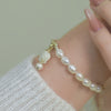 A freshwater pearl bracelet with small gold beads centerpiece, and a floral dangle.
