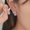 Wimsico blue shell earring is worn on the the ear. The model showcased the other blue starfish pearl earring  by holding it up with her hand.