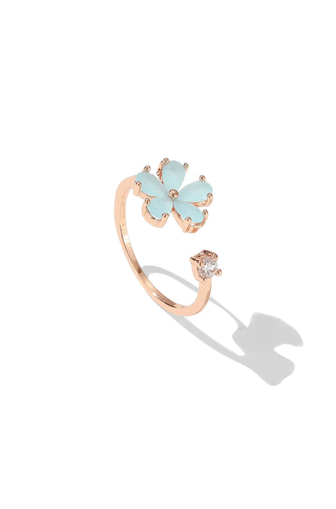 Dainty gold rings featuring gemstone flower, with a small clear stone on the opposite end.